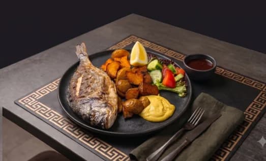 Frisch gegrillte Dorade mit Röstkartoffeln, Salat und Zitrone im Ariston Rerik